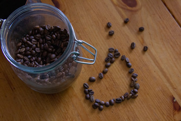 coffee in a glass jar stands on a wooden table. a heart of coffee beans
