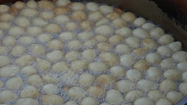 4K Close up zoom out Boiling round doughnuts in oil