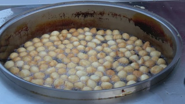 4K Zoom out stirring doughnuts frying in oil