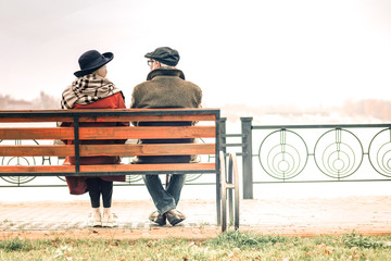 Back view of a elderly couple relaxing on bench in park