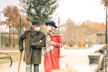 Elderly couple wearing face masks walking in park