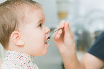 mom in the kitchen is feeding the baby milk porridge
