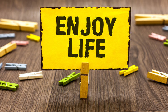 Text sign showing Enjoy Life. Conceptual photo Any thing, place,food or person, that makes you relax and happy Clothespin holding yellow paper note several clothespins wooden floor