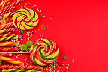 Colorful candies on a red  background. Lollipop. Top view. Copy space.