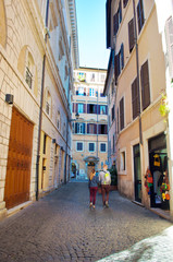 Fototapeta premium Young man and woman walking down a narrow solitary street in the city center of Rome