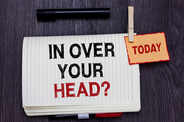 Handwriting text writing In Over Your Head question. Concept meaning To be involved in a difficult situation problem Written paper on wooden desk paper clip grip note with red words black pen