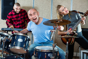 Expressive drummer with his bandmates practicing in rehearsal room