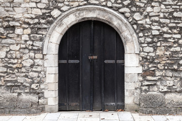 Closed black wooden door in stone wall