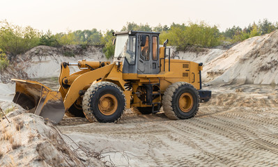 Obraz na płótnie Canvas Wheel loader excavator at work. Bulldozer loading sand.
