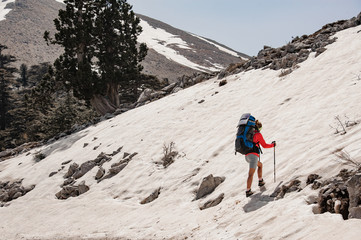 Female tourist with hiking equipment in snowy mountains