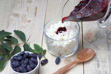 Fresh honeysuckle berries and jam, natural cottage cheese on a wooden table, breakfast concept in...