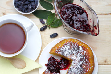 Cottage cheese casserole with icing sugar and fresh honeysuckle berries, jam, a cup of tea, a...