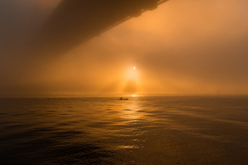 Obraz premium Silhouette of a person on a kayak under the foggy sun.