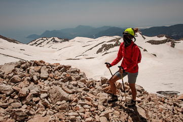 Female wanderer with walking sticks in mountains