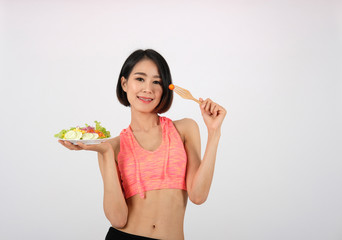 sporty fitness woman in sportswear with vegetable salad on white background. healthy sport