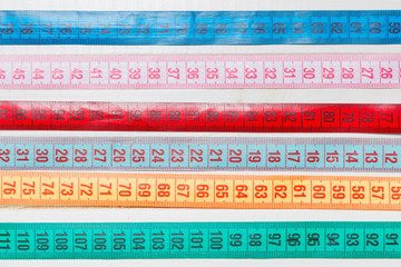 Close up of a group of colorful measure tapes lying in rows as a background. Diet concept on wooden...