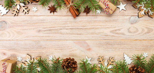 Christmas background with fir tree and gift box on wooden table. Top view banner with copy space...