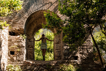 Young girl in light dress under ruined arc