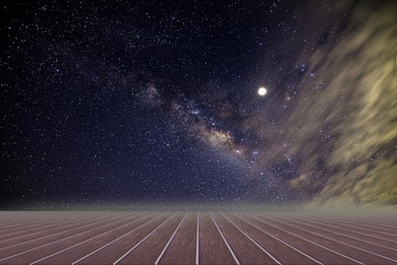 Fototapeta na wymiar Wooden floor and backdrop of the Milky Way sky at night