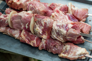 Fresh pickled meat sliced into barbecue skewers in a garden
