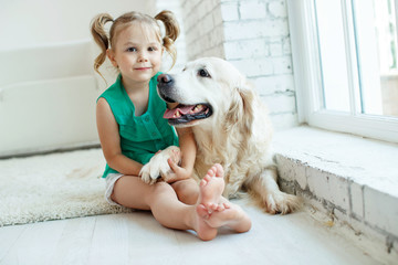 A child with a dog. Girl with a Labrador at home. 