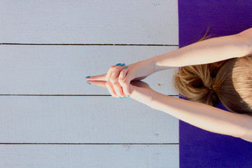 Woman practicing outdoors on violet yoga mat. Overhead close up of female hands in mudra on white...