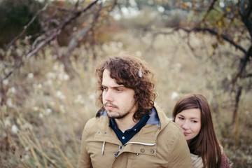 Fototapeta premium Young happy caucasian couple expecting a baby. Pregnant woman and her husband walking and having fun together outdoors in the autumn. Family, parenthood, love, happiness concept.