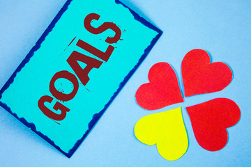 Text sign showing Goals. Conceptual photo Desired Achievements Targets What you want to accomplish in the future written Sticky Note paper plain background Paper Love Hearts next to it.