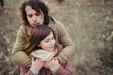 Fototapeta premium Young happy caucasian couple expecting a baby. Pregnant woman and her husband walking and having fun together outdoors in the autumn. Family, parenthood, love, happiness concept.
