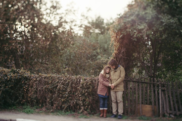 Naklejka premium Young happy caucasian couple expecting a baby. Pregnant woman and her husband walking and having fun together outdoors in the autumn. Family, parenthood, love, happiness concept.