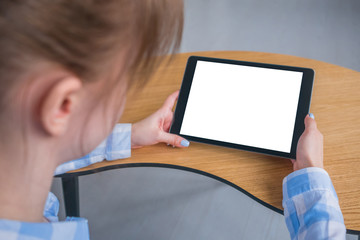 Woman sitting at wooden table and looking at black digital tablet computer device with white blank screen. Mock up, entertainment, copyspace, template, leisure time and technology concept