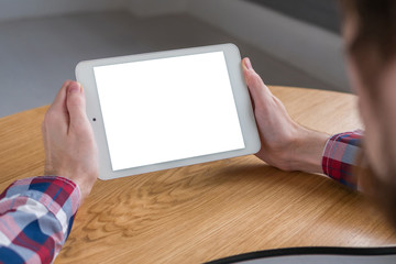 Mockup image: over shoulder close up view of man looking at modern digital tablet computer device with white blank screen. Mock up, copyspace, leisure time, template and technology concept