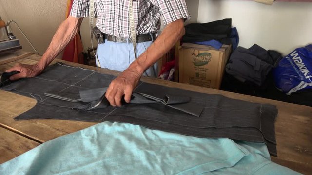 Yesiluzumlu village, Mugla, Turkey - 71th of July 2019: 4K Old tailor working on cutter garment trousers
