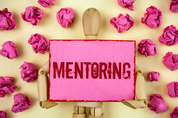 Handwriting text Mentoring. Concept meaning To give advice or support to a younger less experienced person written Sticky Note paper holding by Wooden Robot Toy plain background Paper Balls.