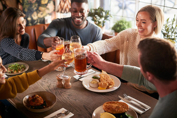 Friends Meeting For Meal In Traditional English Pub Making Toast Together