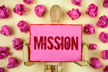 Handwriting text Mission. Concept meaning Corporate goal Important Assignment Business purpose and focus written Sticky Note paper holding by Wooden Robot Toy plain background Paper Balls.