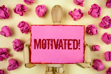 Handwriting text Motivated Motivational Call. Concept meaning Willing to do something Inspired Confident written Sticky Note paper holding by Wooden Robot Toy plain background Paper Balls.