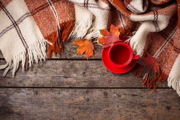 Autumn background with cup of tea, plaid and leaves