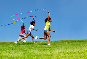 Happy three girls jump, wave with ribbon over sky