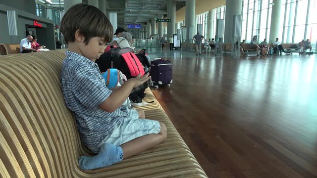 Dalaman Airport, Turkey - 18th of June 2019: 4K Kid plays with tablet waiting for their flight in the airport lounge