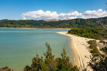 A view through the trees of an inlet and beach at the incredibly beautiful Able Tasman National Park, South Island, New Zealand