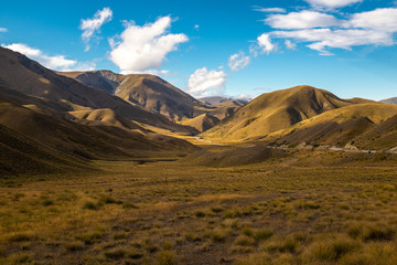 The stunning brown landscape of the rolling hills and mountains of the Lindis Pass, New Zealand