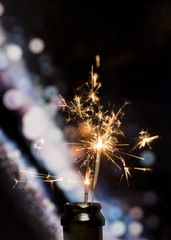 Close-up of burning sparkler in bottle on bokeh background