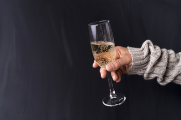 Man's hand holding glass of champagne against black background