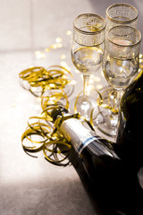 Fototapeta premium Close-up of empty champagne bottle and glass with golden streamers at party