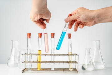 Male's hands holding chemistry lab's test tubes, putting them back in the tube holders