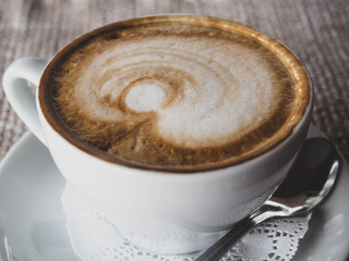 White cup of coffee on vintage burlap table cloth. Top view.
