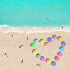 Fototapeta na wymiar People on beach and heart shape made of umbrellas