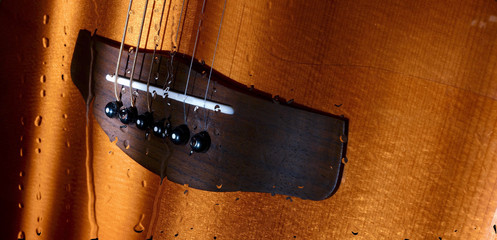guitar in the sun light behind the glass with water drops . color background