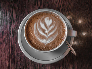 Hot coffee in a cup with foam milk beautiful latte art on wooden table background. Cappuccino or latte art, Toned